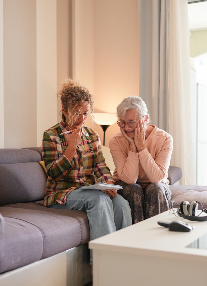 Smiling Senior Woman And Caregiver Sharing A Moment Sitting,